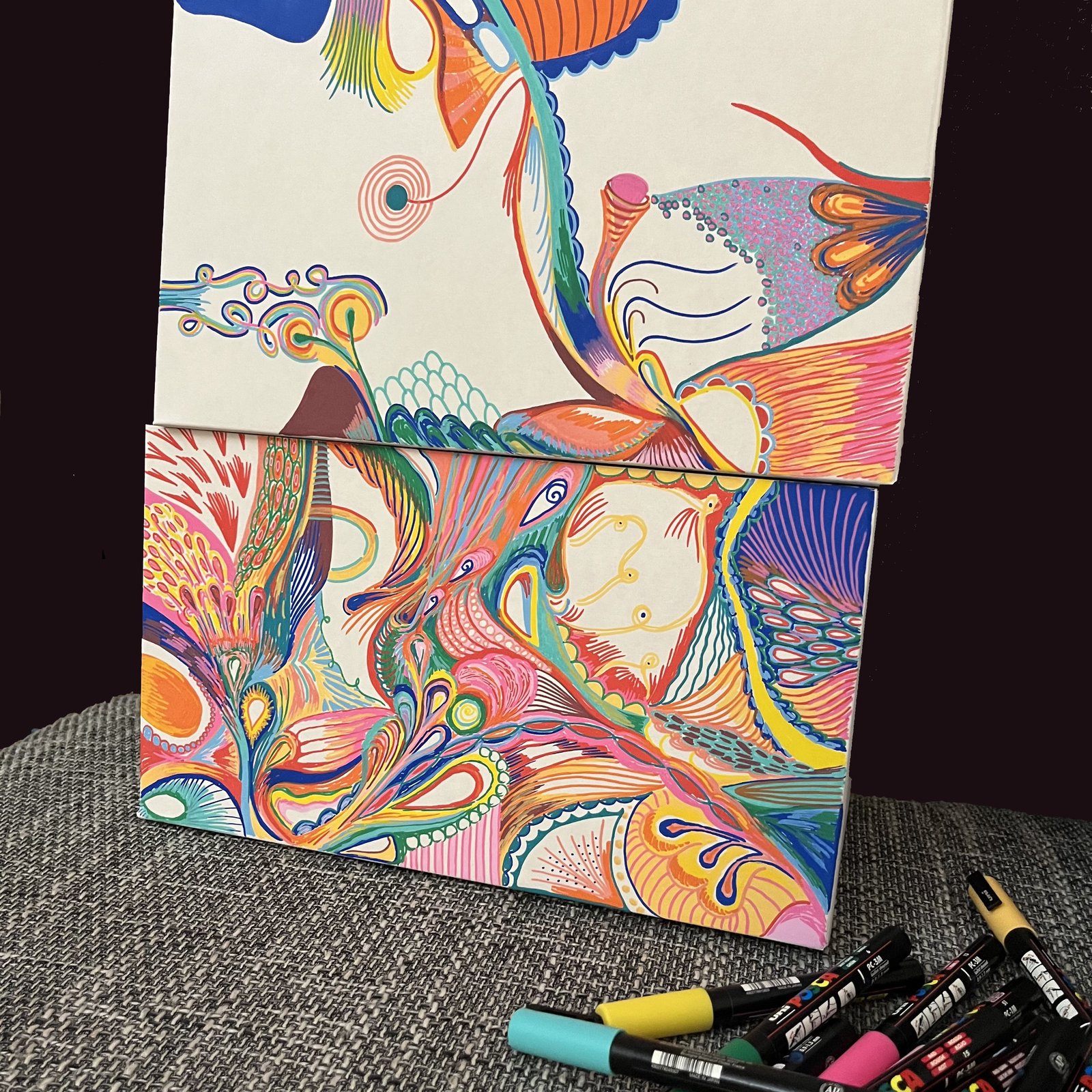 Zwei farbenfrohe Leinwandbilder mit abstrakten organischen Formen neben Markern