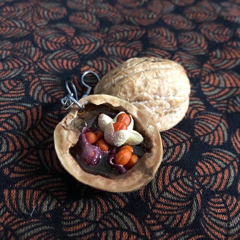 Walnuss-Anhänger mit bunten Miniatur-Elementen auf gemustertem Stoff