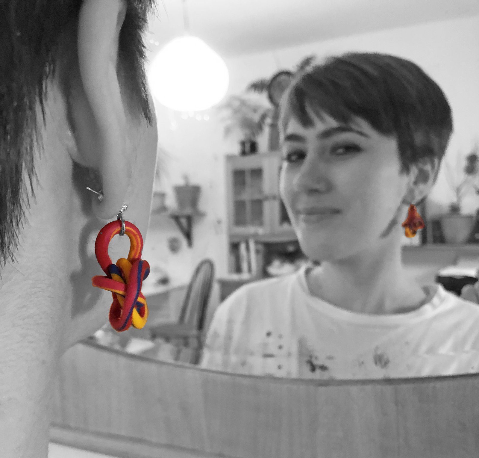 Rot-gelbe verschlungene Ohrringe aus Modelliermasse, Schwarz-Weiß-Portrait mit Farbakzent