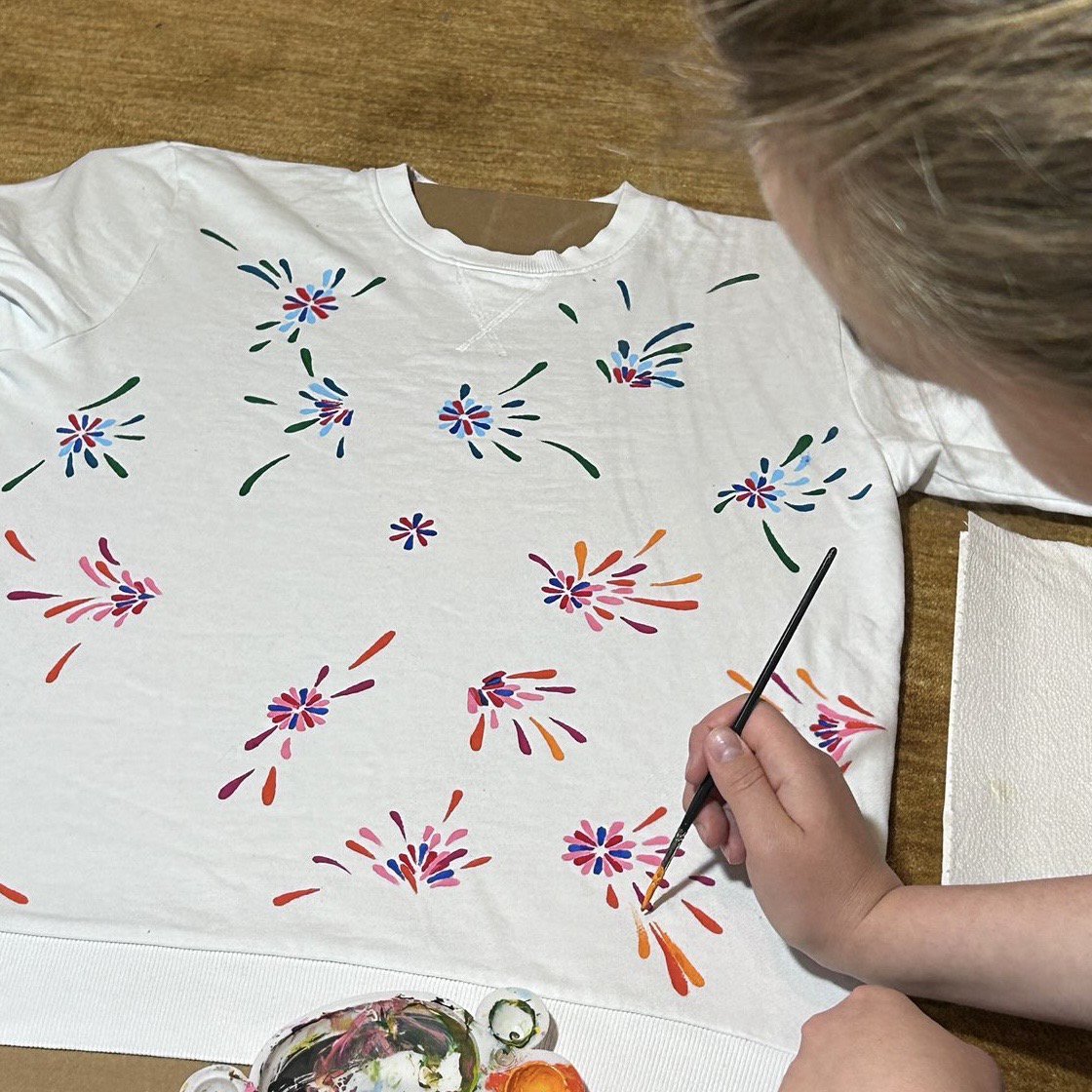 Künstlerin malt bunte Blumenmotive auf ein weißes T-Shirt